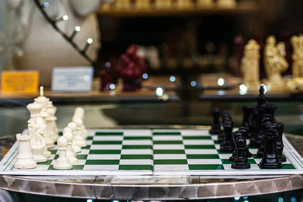 A table with a chess board and figures on the side of the street at a board game shop