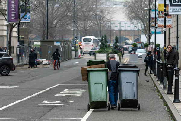 После празднования Нового года мужчина очищает улицу и вывозит мусорные баки. — стоковое фото