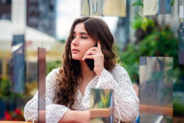 Bir akıllı telefon kullanan bir genç, sempatik, esmer kadın. Bir ayna yüklemesi aracılığıyla bir kadın portresi.