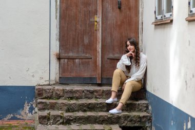 Eski bir ev merdivenlerde oturan bir genç, güzel, esmer kadın. Kopya alanı.