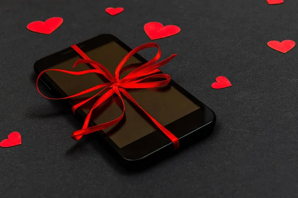 Valentine day, Christmas gift concept, on dark background isolated red paper hearts and smartphone with red ribbon - image — ストック写真