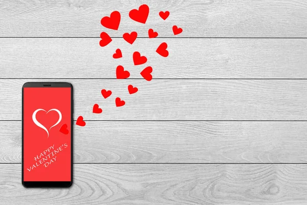Valentine day concept, love message - hearts flying out smartphone, isolated on white wooden background, greeting on smartphone screen — Stockfoto
