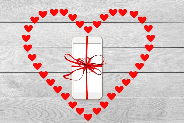 Valentine day, Christmas gift concept, on white wooden background isolated heart shape from red paper hearts and smartphone with red ribbon - image — ストック写真