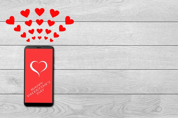 Valentine day concept, love message - hearts flying out smartphone, isolated on white wooden background, greeting on smartphone — Stockfoto