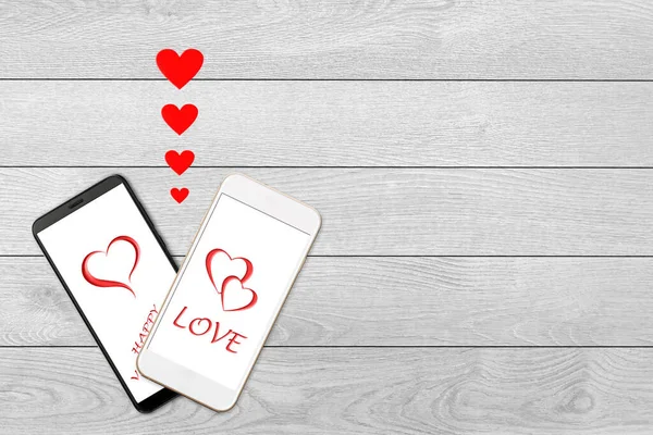 Концепція дня Святого Валентина, любовне повідомлення - серця, що вилітають зі смартфона, ізольовані на білому дерев'яному фоні, привітання на екрані смартфона — стокове фото