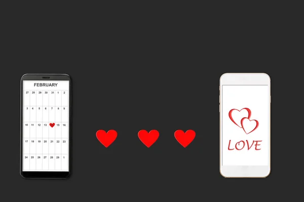 Valentine day concept, on dark background isolated red paper hearts and two smartphones, calendar and greeting on smartphone screen — Stockfoto