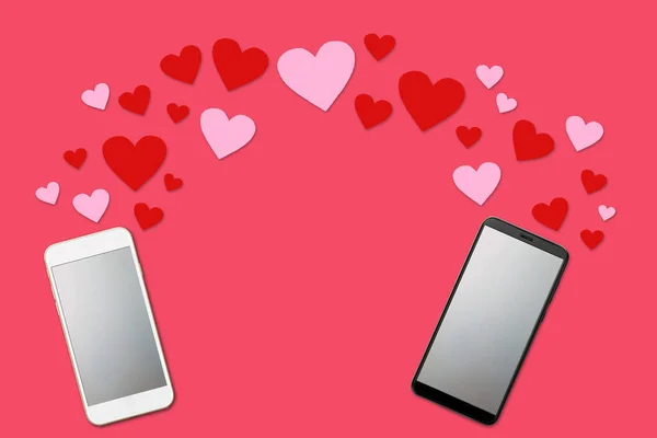 Концепція дня Святого Валентина, любовне повідомлення - серця, що вилітають з двох смартфонів з порожнім екраном, ізольовані на рожевому фоні, плоска лежала — стокове фото