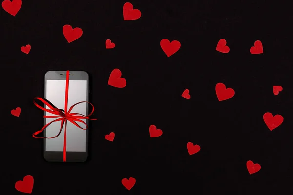 Alla hjärtans dag, Julklapp koncept, på mörk bakgrund isolerad rött papper hjärtan och smartphone med rött band, platt låg — Stockfoto
