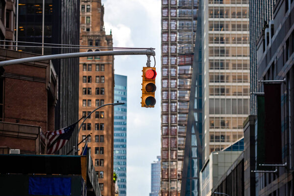 Traffic light with red light above Manhatan street among many skyscrapers, New York, USA