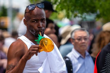 Brooklyn, New York, ABD - 22 Haziran 2019: Coney Adaları yıllık deniz kızı geçit töreni, Afrikalı bir adam kalabalığın içinde duruyor ve ferahlatıcı bir içecek içiyor