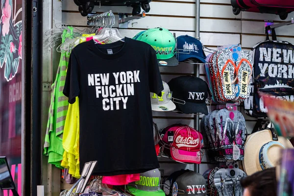 New York, USA - June 23, 2019: many t-shirts and souvenirs for sale in a tourist gift shop — Stock Photo, Image