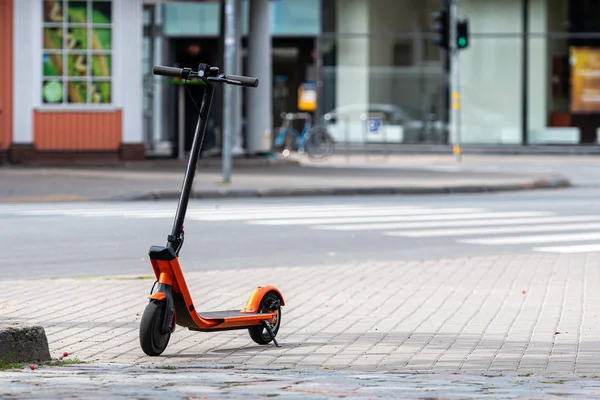 Scooter eléctrico o e-scooter estacionado en la acera, borrosa ciudad calle fondo —  Fotos de Stock
