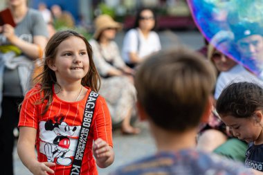 Old Town Square, Riga, Latvia - August 16, 2019: Children playing with colorful soap bubbles floating in the foreground