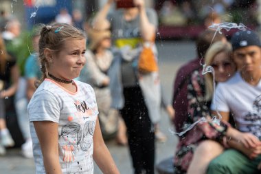 Old Town Square, Riga, Latvia - August 16, 2019: Children playing with colorful soap bubbles floating in the foreground