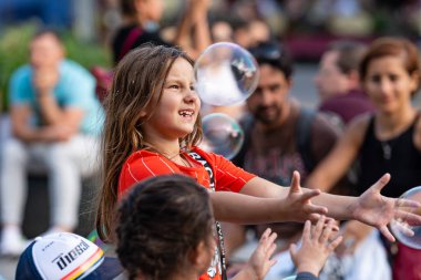Old Town Square, Riga, Latvia - August 16, 2019: Children playing with colorful soap bubbles floating in the foreground