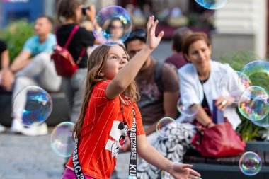 Old Town Square, Riga, Latvia - August 16, 2019: Children playing with colorful soap bubbles floating in the foreground