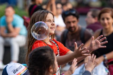 Old Town Square, Riga, Latvia - August 16, 2019: Children playing with colorful soap bubbles floating in the foreground