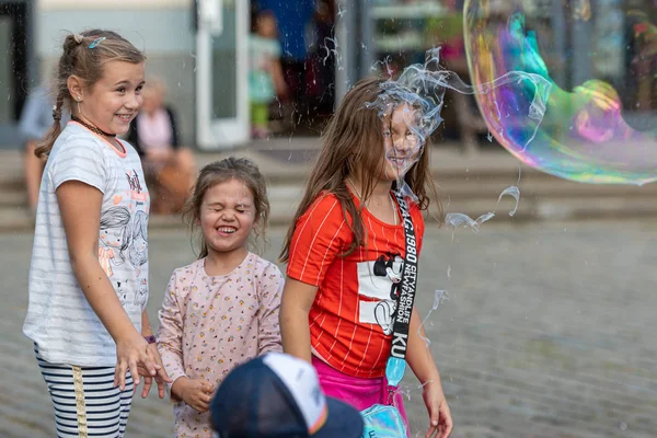 Staroměstské náměstí, Riga, Lotyšsko - 16. srpna 2019: Děti si hrají s barevnými mýdlovými bublinami plovoucími v popředí — Stock fotografie