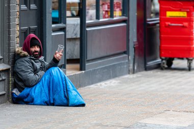 Londra, İngiltere, Uk - 2 Ocak 2020: kaldırımda oturan ve yoldan geçenlerden dilenen sakallı bir adam
