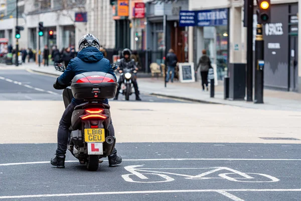 Лондон, Англия, Великобритания - 2 января 2020 года: человек на скутере ждет светофора на перекрестке центра города, вид сзади — стоковое фото