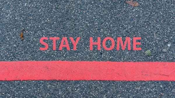 トップ赤い線とテキストを持つアスファルトの道路の眺め Stay Home 制限や安全警告の概念 — ストック写真