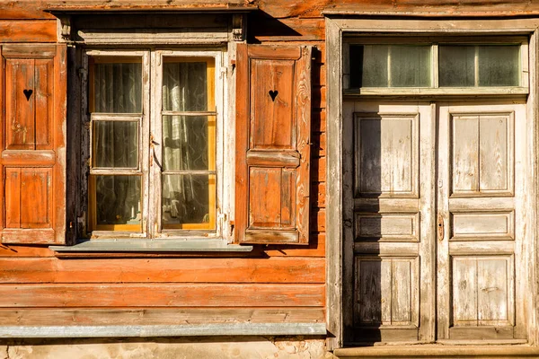 windows with open shutters and closed doors of an old wooden house on a sunny day