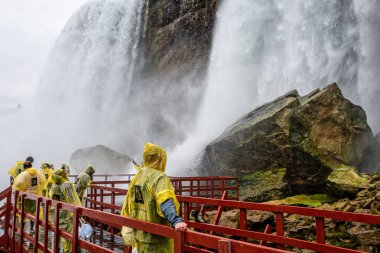 Niagara Şelalesi, New York, ABD - 13 Haziran 2019: Islak ahşap merdivenlerde yağmurluk giyen ziyaretçiler Amerikan Şelaleleri 'nin suları altında bir tura çıkarlar.