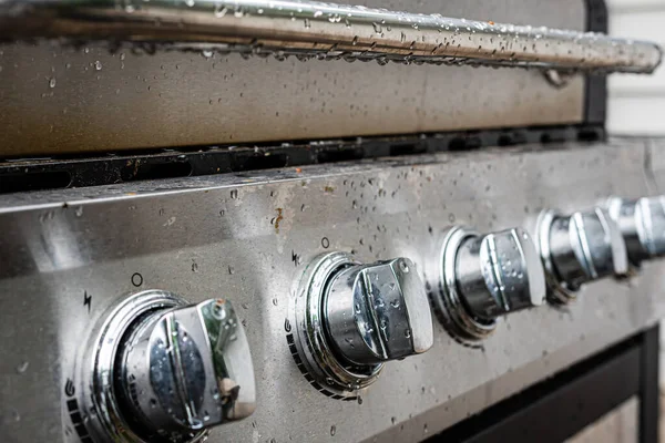 Elektrik paslanmaz çelik ızgaranın düğme panelindeki su damlaları, yakın plan.