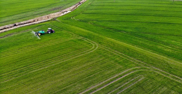 拖拉机在绿色的大麦田上喷洒化学药品的航拍图 — 图库照片