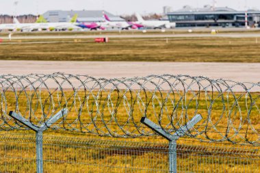 Riga, Letonya - 17 Nisan 2020: Coronavirüs salgını karantinası, uçuşlar iptal edildi, dikenli tellerin arkasında görünür bir uçak, Riga Uluslararası Havaalanı 'nda uzun süre park edilmiş, seçici odaklı.