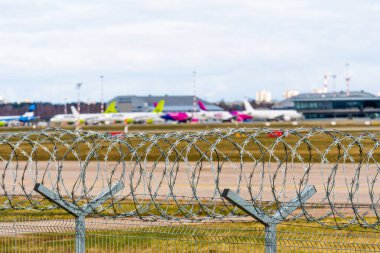 Riga, Letonya - 17 Nisan 2020: Coronavirüs salgını karantinası, uçuşlar iptal edildi, dikenli tellerin arkasında görünür bir uçak, Riga Uluslararası Havaalanı 'nda uzun süre park edilmiş, seçici odaklı.