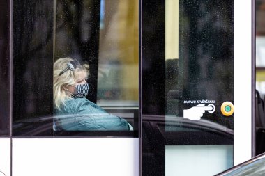 Riga, Letonya - 14 Mayıs 2020: Coronavirus 'tan korunmak için bir maske takan kadın bir tramvayın penceresinden görüldü.
