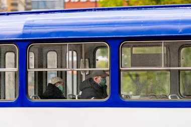 Riga, Letonya - 14 Mayıs 2020: tramvay yolcuları tıbbi maskeli, yarı çıplak bir toplu taşıma aracının penceresinden Coronavirus Önleme