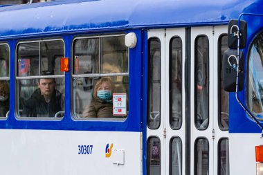 Riga, Letonya - 14 Mayıs 2020: Tramvay yolcuları tıbbi maske takıyor, yarısı boş bir toplu taşıma aracının penceresinden bakıyor, Coronavirus Önleme