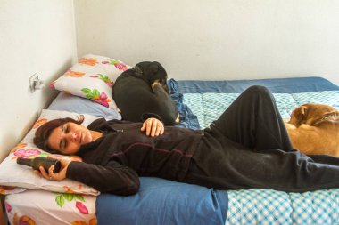 Sarhoş kız yatak odasındaki şişeden içiyor ve yanında sevgili köpeği var.