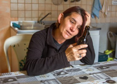 Mutfaktaki şişeden içen sarhoş kız masanın üstünde.