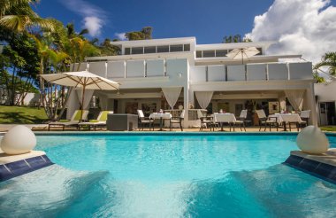 25 Mayıs 2018 'de Dominik Cumhuriyeti' nin Sosua şehrinde havuz kenarındaki merdivenler, palmiye ağaçları ve muhteşem bir dinlenme odası olan güzel bir tatil köyü.