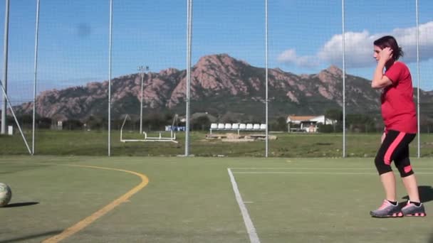 Uma linda garota que marca em um campo de futebol 5-a-side — Vídeo de Stock