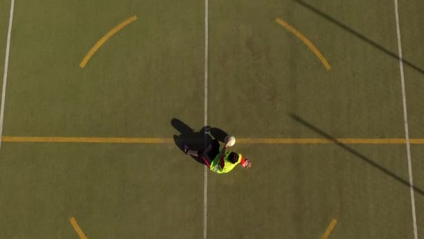 Aerial view of girl player sitting with a great shadow with the ball by her side in a 5-a-side football field — Stock Video