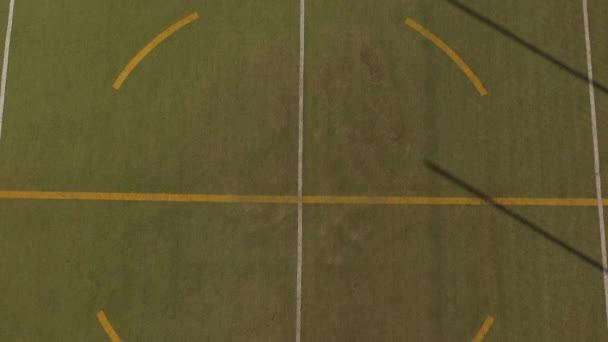 Vista aérea da menina sentada com uma grande sombra com a bola ao seu lado em um campo de futebol 5-a-side — Vídeo de Stock