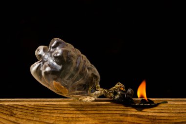 Plastik bir şişenin kapağı yavaşça yanarak duman üretir ve kendisini geri dönüşüm ve çevre kirliliğinin bir sembolü olarak tüketir.