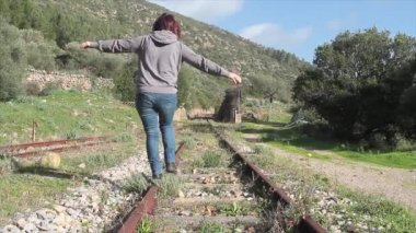 Kız bir tren istasyonunda dengede yürüyor.