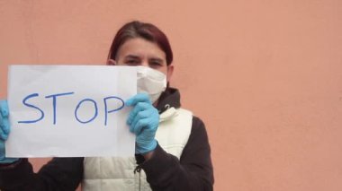 Beyaz işaretli kadın, beyaz sağlık maskesi ve mavi doktor eldiveni takmayı bırak diyor. Virüs tipi Coronavirüs 'e ya da Cvid 19' a meydan okuyor.