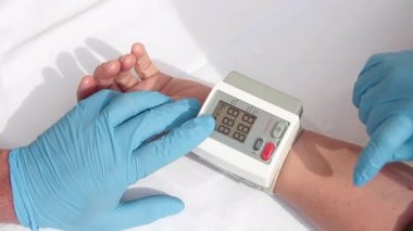 Mavi eldivenli doktor, kan basıncı ve kalp atışlarını ölçerek hastanın üzerinde dijital sfenometre kullanmaya hazırlanıyor.