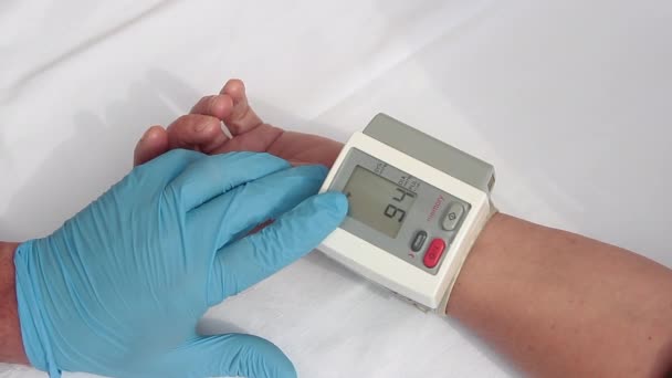 Lekarz w niebieskich rękawiczkach przygotowujący się do stosowania sfigmomanometru cyfrowego u pacjenta poprzez pomiar ciśnienia krwi i tętna — Wideo stockowe