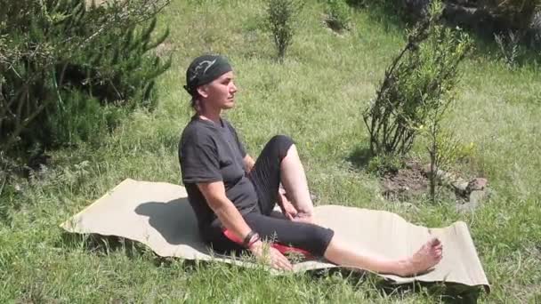 Mujer haciendo estiramiento y yoga en una alfombra de bambú en el centro del jardín con hierba verde y plantas que oscilan en el aire brillante de primavera — Vídeo de stock