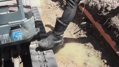 Kadın kazıcı sarı uyarı yeleğiyle küçük bir kazıcıya gidiyor. Hijyenik koruyucu maske takıyor. Bu da her şeyi yoluna koyuyor.