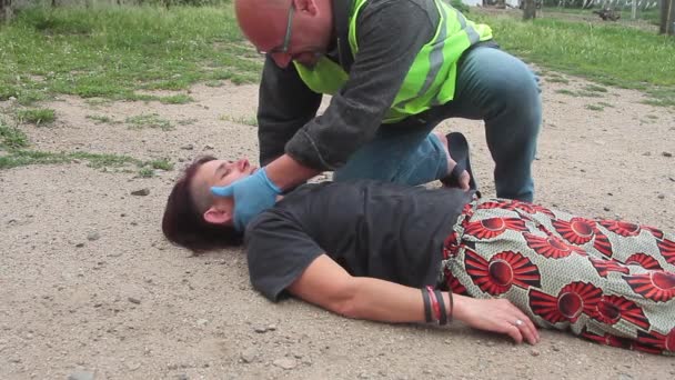 Médico de emergência com casaco amarelo que intervém para uma reanimação de uma mulher com respiração boca a boca — Vídeo de Stock