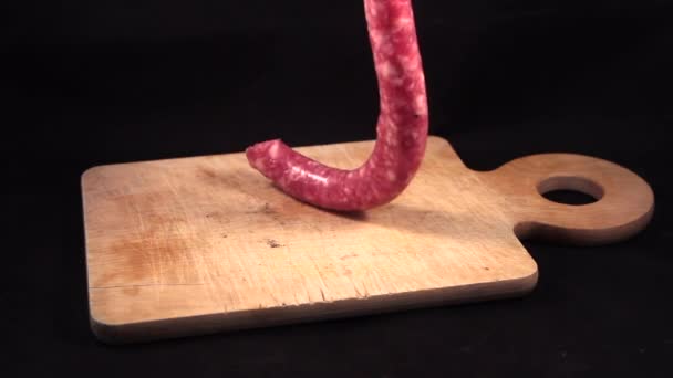 Deliciosa salsicha de porco rosa italiana fresca colocada em uma placa de corte de madeira no fundo preto — Vídeo de Stock