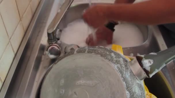 Side view of woman hands washing dishes with pots and cutlery with foam and water — Stock Video